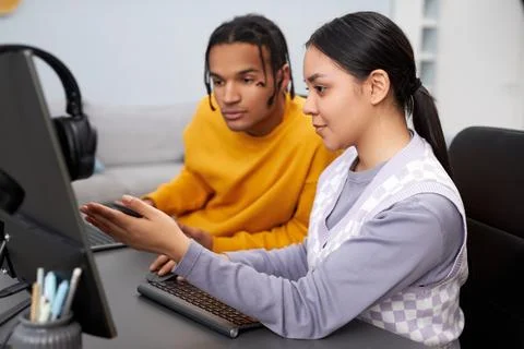 Two young people writing code in office woman pointing at computer screen Stock Photos