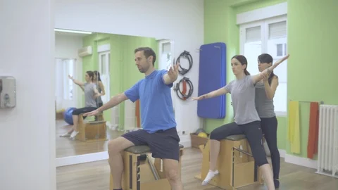 Two young pilates students and instructor working their body with a wunda chair Stock Footage 126977706