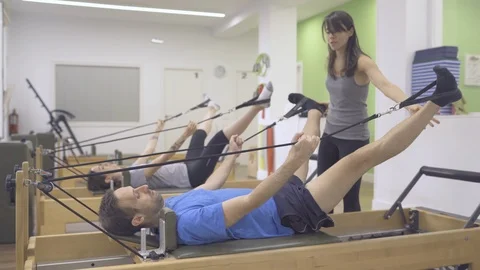 Two young pilates students working their lower body with a reformer bed. Stock Footage 126977225