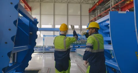 Two young positive workmen in uniform walk and dance between equipment in large Stock Footage 121099295