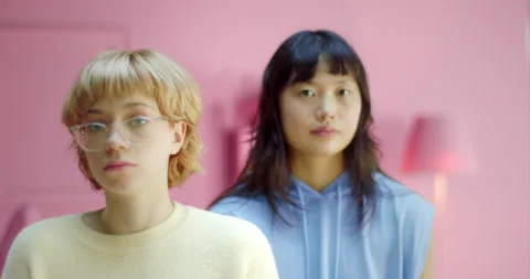 Two young pretty diversity lesbian couple looking at the camera at home with Stock Footage 163647565
