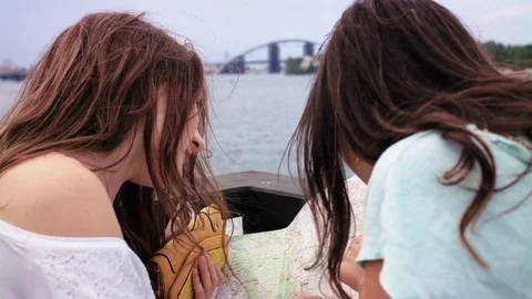 Two young pretty girls looking at the paper map. Women looking for interesting Stock Footage 74483153