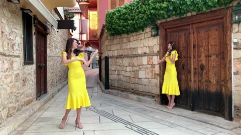 Two young pretty twin sisters violinists in yellow concert dresses are playin Stock Footage 130882817