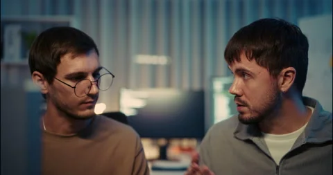 Two Young Programmers Discussing Code in Modern Tech Office at Night. Video stock 306739920