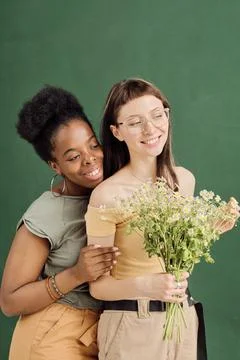 Two young romantic lesbian dates with flowers standing in front of camera Stock Photos