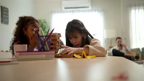 Two young school children are happily playing a game of Jenga, Видео 340908185