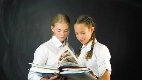 Two young school girls in class holding exercise books  Stock Footage 136505834