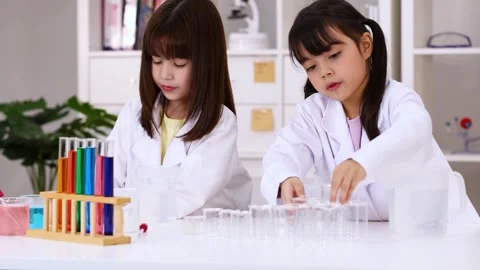 Two Young School Girls in Lab Coats Conducting Science Chemistry Experiment Stock Footage 345022908