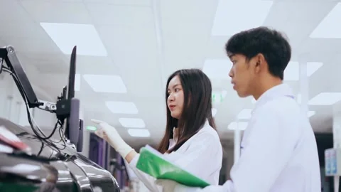 Two young scientist looking at results from automation blood analyzer reported Stock Footage 133444825