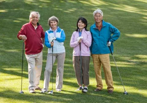 Two young senior golfing couples on the course and ready to play. Fotos Stock