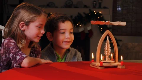 Two young siblings share the magic of the holidays watching a Christmas pyramid. Stock Footage 130150448