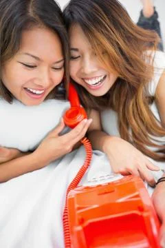 Two young sisters having fun with a telephone 库存照片