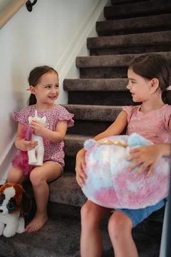 Two young sisters playing with stuffed animals on stairs Stock Photos