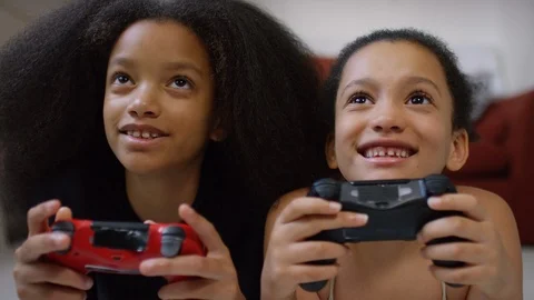 Two young sisters playing video games together at home Stock Footage 96312011