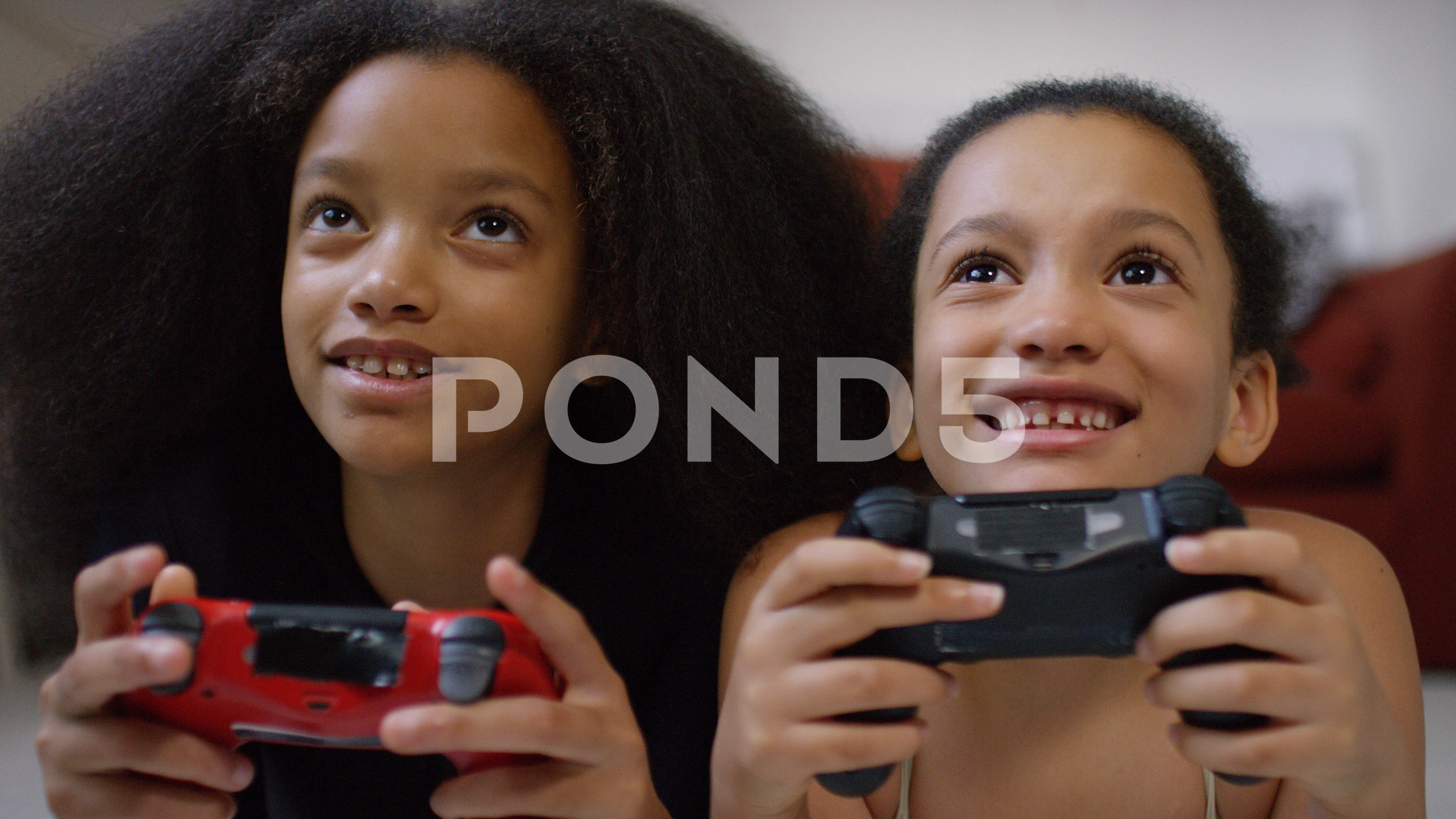 Two young sisters playing video games together at home