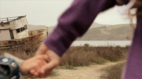 Two young sisters running hand in hand by a lake. Stockbeeldmateriaal 88342942