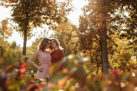 Two young sisters stand in the sunlight with their eyes closed and smile. Stock Photos