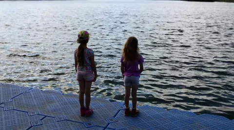 Two young sisters standing on shore of lake Stock Footage 60100791