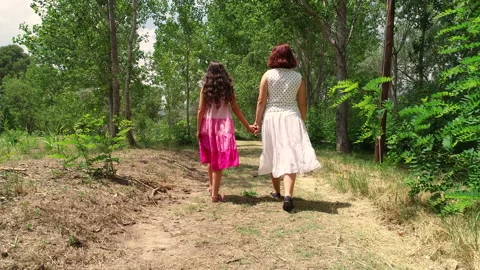 Two young sisters walk hand in hand through the forest from behind Stock Footage 142639580