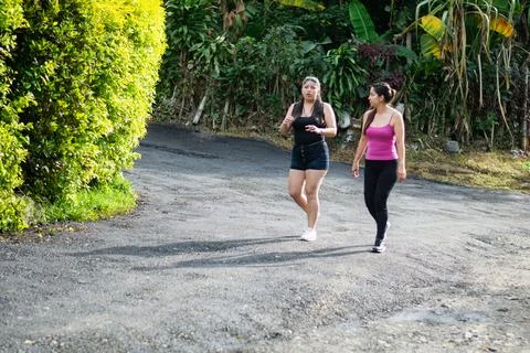 Two young sisters walking toward the camera while talking during a relaxing.. Stock Photos