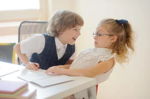 Two young student, boy and girl sitting at a school desk. Stock Photos