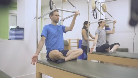Two young students and instructor exercising their bodies with a cadillac bed. Video stock 126981703