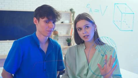 Two young students draw geometric shapes on glass with a marker and look at them 写真素材
