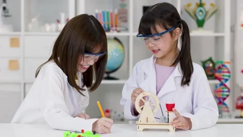 Two Young Students in Lab Coats Conducting Science Experiment in Classroom Stock Footage 340244419
