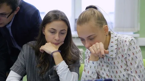Two young students sitting at the table in the audience and discussing the task Stock Footage 70755179