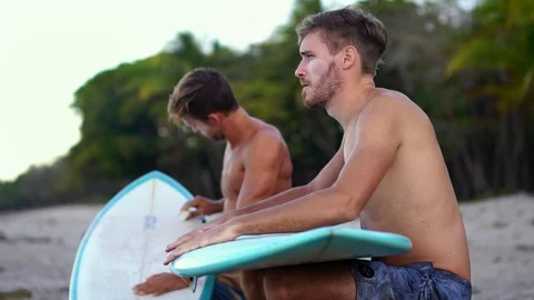 Two young surfer friends on beach with surfboards at sunrise.  Stock Footage 108564239