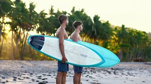 Two young surfer friends on beach with surfboards in beautiful golden sunrise  Stock Footage 108564253