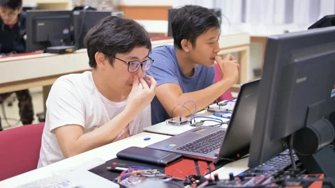 Two young Thai engineers are programming a computer software at the Stock Footage 115921779