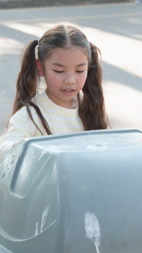 Two Young Thai Girls Disposing of Plastic Trash in Park Bin Stock Footage 336657461