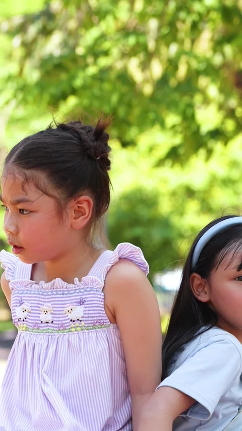 Two Young Thai Sisters Sitting Back to Back in Lumpini Park Stock-Footage 334639150