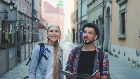 Two young tourists checking map while walking on main tourist street Stock Footage 142977334