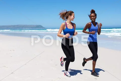 Two young woman running on the sea shore Stock Photos