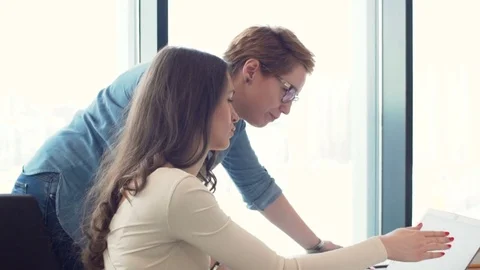 Two young woman work together on laptop and papers in office Stock Footage 73519642