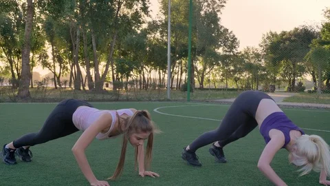 Two young womans stretching on soccer field in park, weight loss, fitness models Stock Footage