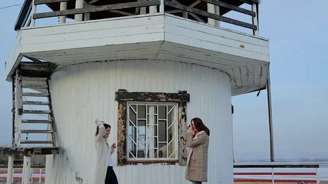 Two young women are photographed on the background of the lighthouse. Stock Footage