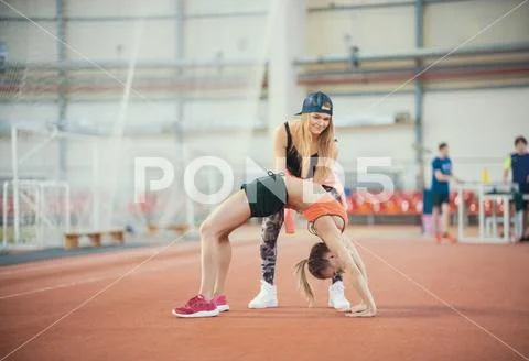 Two young women with blonde hair doing exercises and breathing hard in the sp Stock Photos