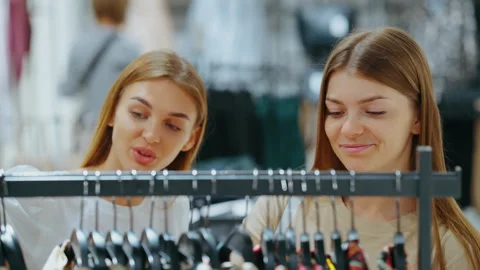 Two young women browsing clothes on rack in store Stock Footage 324806635