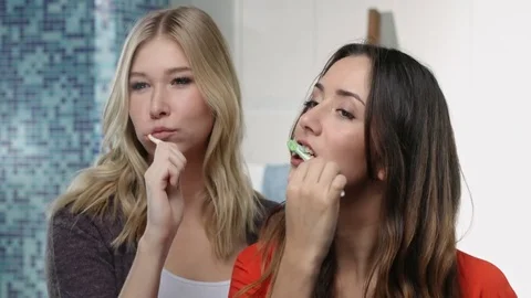 Two young women brushing teeth together infront of the camera Video stock 76782860