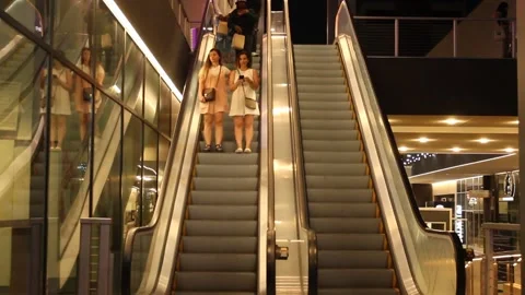 Two Young Women Coming Down Escalator at Night Conservatively Dressed Stock Footage 170469832