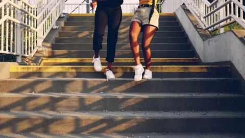 Two young women dance while going down the stairs in the city Stock Footage 161085480