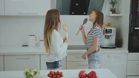 Two young women dancing and singing in the kitchen. Good mood when cooking 库存影片 112170833