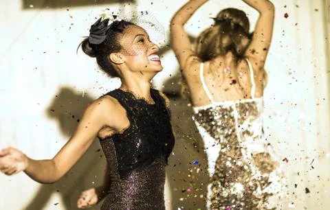 Two young women dancing with confetti falling. Stock Photos