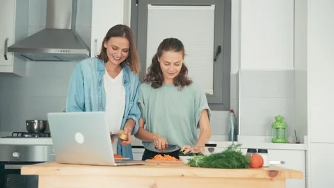 Two young women dancing while cooking and talking with friends via the internet Stock Footage 128128597