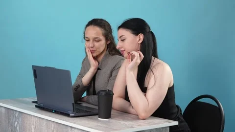Two Young Women Discussing Project Work on Laptop Against Blue Background Stockbeeldmateriaal 346110959