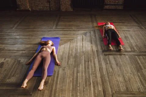 Two young women do complex of stretching yoga asanas in loft style class Stock Photos