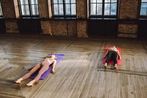 Two young women do complex of stretching yoga asanas in loft style class Stock Photos